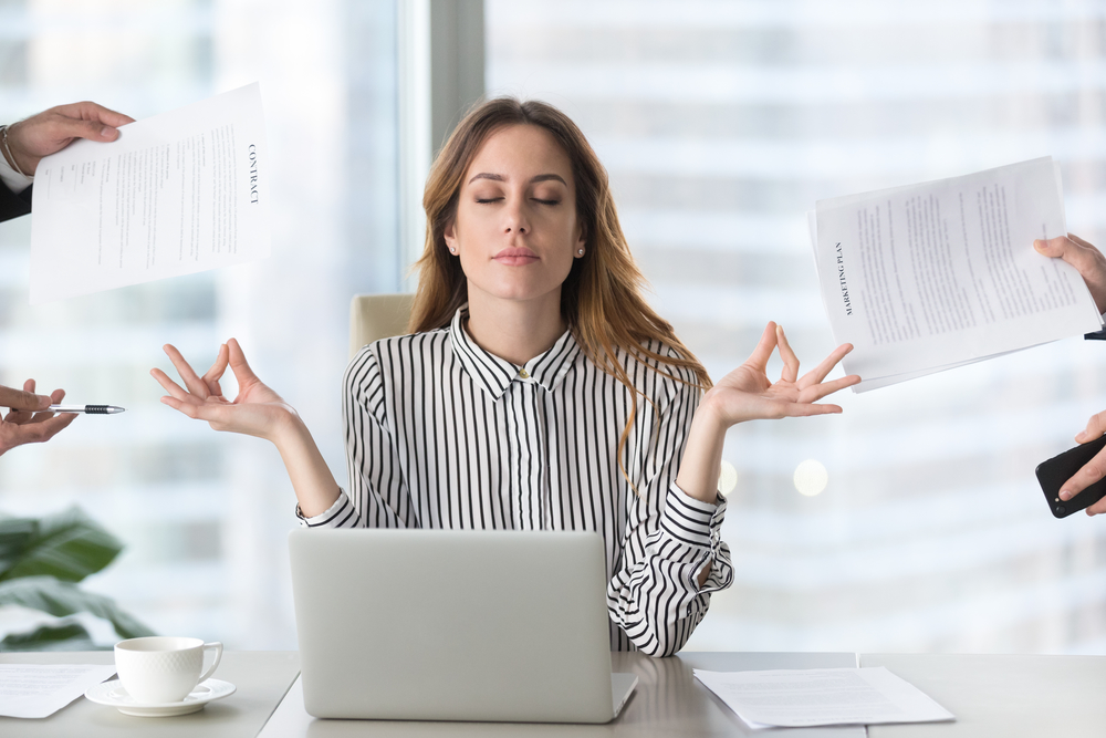 Calm female executive meditating taking break avoiding stressful job