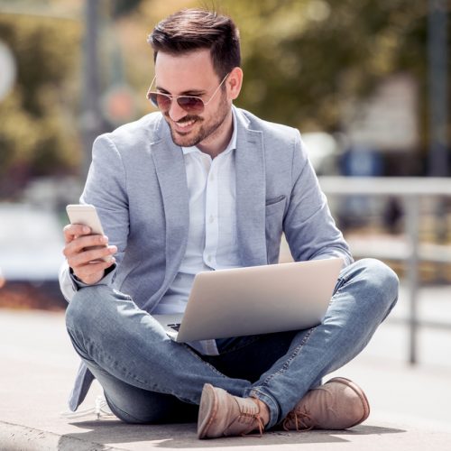 Young attractive man sitting outside ,using cell phone
