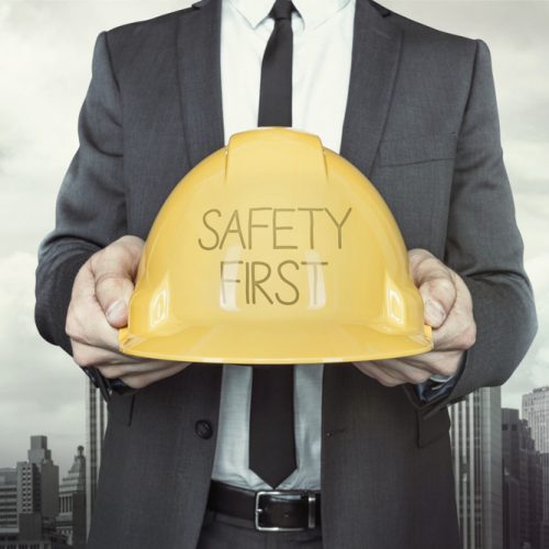 Safety first text on helmet what businessman is holding