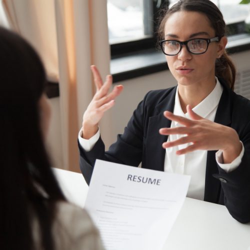 Confident millennial female applicant in glasses talking at job
